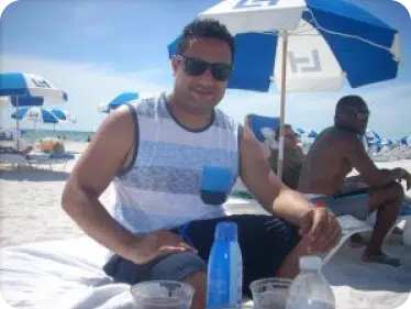 Smiling man wearing sunglasses at a beach 